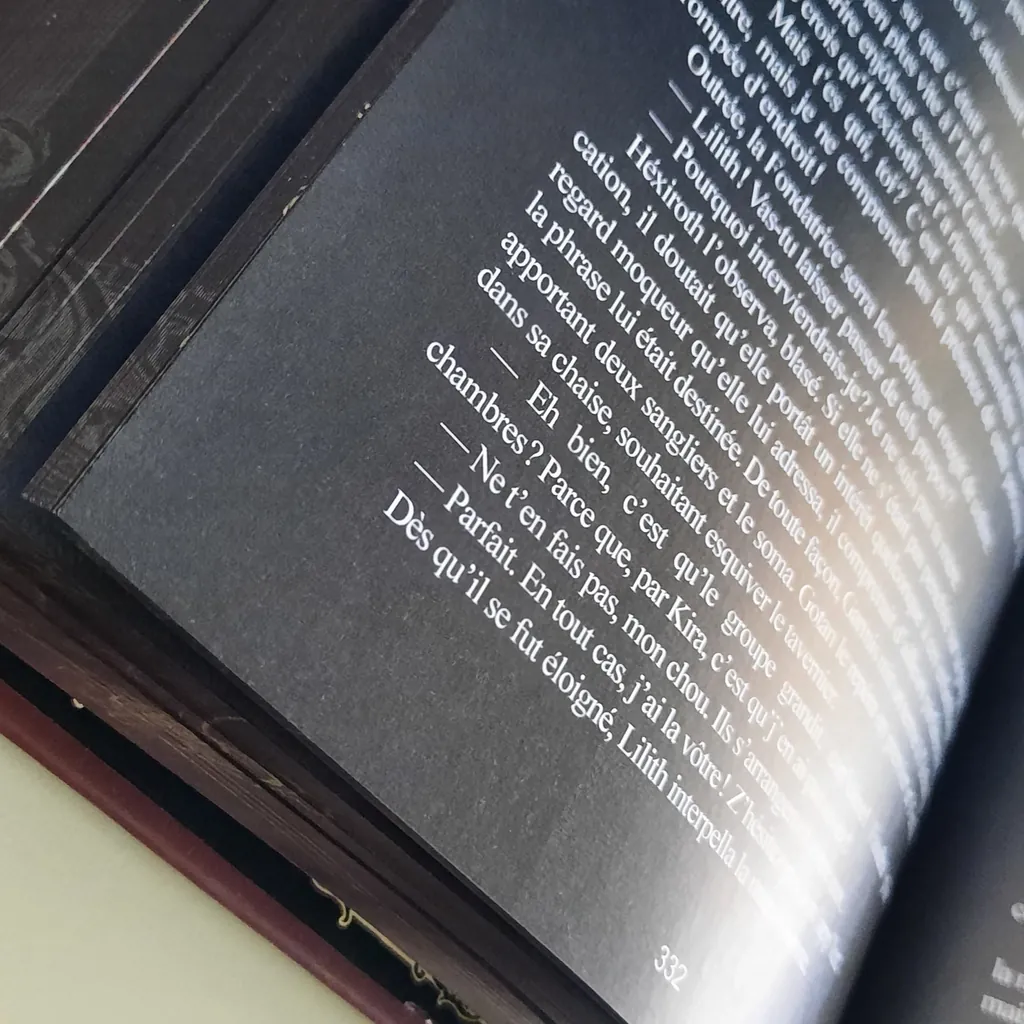 Gros plan sur une page noire imprimée en encre blanche, tranches sombres