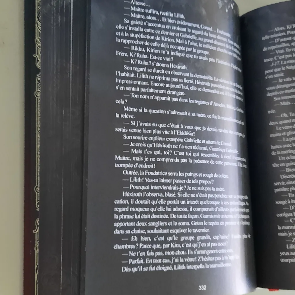 Double page ouverte, texte blanc sur pages noires, tranche du bloc de pages visible